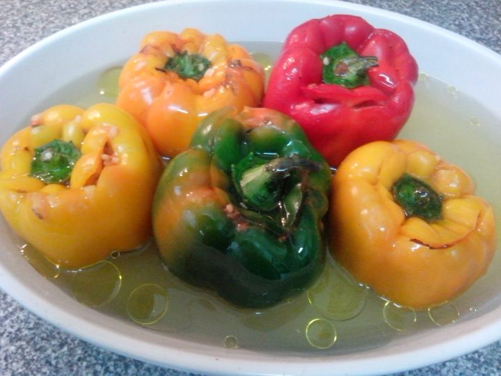 Capsicums stuffed with rice in a baking dish